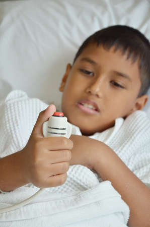 Sick boy pressing a nurse call button の写真素材