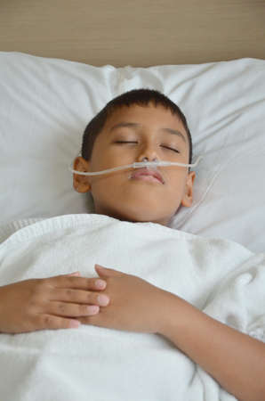 Sick boy sleeping with oxygen line on his nose の写真素材