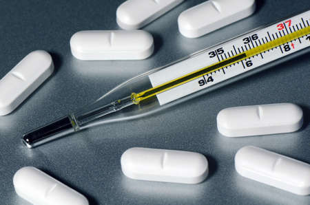 Oral Thermometer and white caplet medicine 