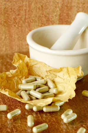 Herbal medicine grinder and filled capsule on brown papers の写真素材