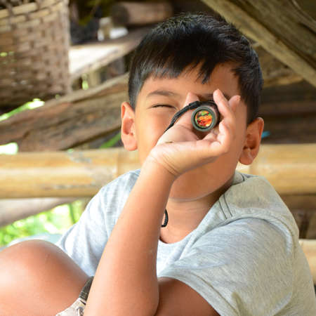 Asian boy playing with his monocular の写真素材