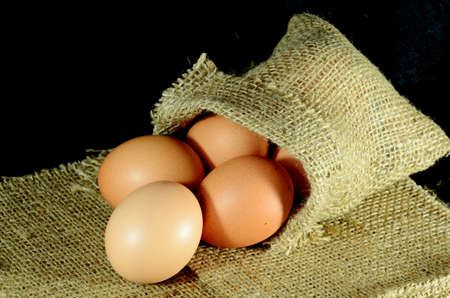 Organic eggs in burlap sac on dark background の写真素材