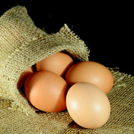 Organic eggs in burlap sac on dark background の写真素材