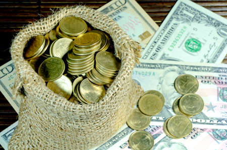Gold Coins in Burlap Sack with Dollar Banknotes Backgroundの写真素材