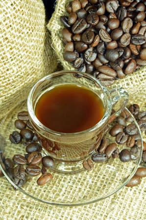 A cup of coffee with roasted coffee beans on burlap sack background の写真素材