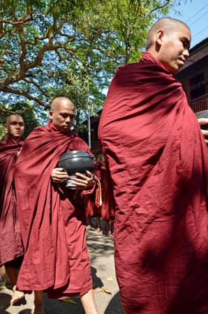  Buddhist novices walk to collect alms and offerings on March 18, 2014 in Maha Ganayon Kyaung, Amarapura near Mandalay, Myanmar のeditorial素材