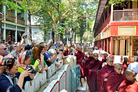  Buddhist novices walk to collect alms and offerings on March 18, 2014 in Maha Ganayon Kyaung, Amarapura near Mandalay, Myanmar のeditorial素材