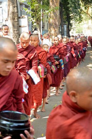 Buddhist novices walk to collect alms and offerings on March 18, 2014 in Maha Ganayon Kyaung, Amarapura near Mandalay, Myanmar のeditorial素材