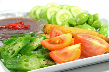 Mixed vegetable menu with sliced cucumber, tomatoes, grilled baby corn, boiled okra and fresh stink beans mostly served with Shrimp-paste sauce in Thai food menu の写真素材