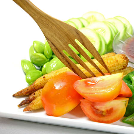 Mixed vegetable menu with sliced cucumber, tomatoes, grilled baby corn, boiled okra and fresh stink beans mostly served with Shrimp-paste sauce in Thai food menu の写真素材