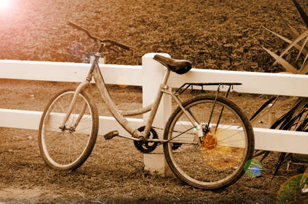 Old Bicycle Lean on the White Fence in the Evening Light の写真素材