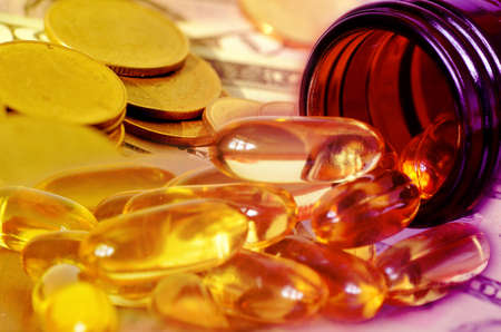 Soft gelatin dietary supplement oil capsule and money in drug expense concept の写真素材