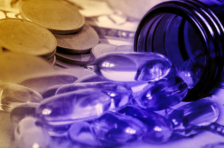 Soft gelatin dietary supplement oil capsule and money in drug expense concept の写真素材