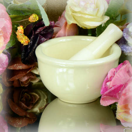 Porcelain herbal medicine grinder on floral background.の写真素材