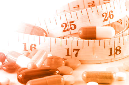 Medicine and Tape Measure on White Background in Waistline and Weight Control Concept.の写真素材