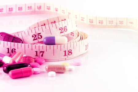 Medicine and Tape Measure on White Background in Waistline and Weight Control Concept.の写真素材