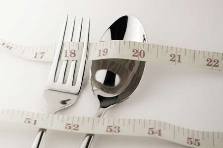Tape Measure, Fork and Spoon in Waistline and Weight Control Concept by Diet Control.