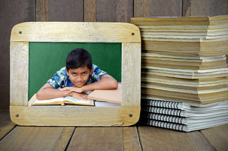 Asian boy in the classroom with Stack of Old Books and Blackboard on Wood Background in Oldies...
