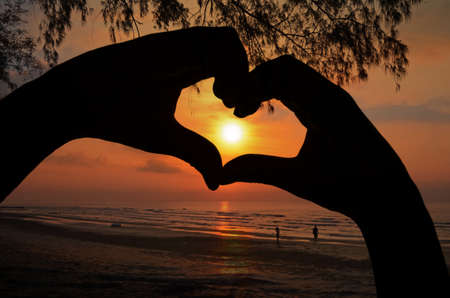 Sunrise in Hand Heart Frame on Beach View.の写真素材