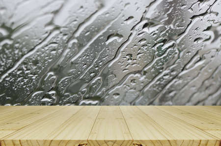 Rain Drops on Glass Window Background with Wood Table.の写真素材