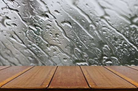 Rain Drops on Glass Window Background with Wood Table.の写真素材