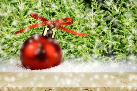 Pine wood table and Red Christmas Ball on Snow with Christmas Tree.の写真素材