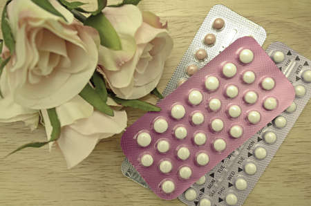 Colorful oral contraceptive pill strips on pine wood table.の写真素材
