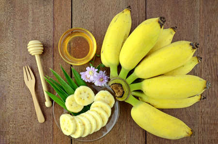 Thai beauty and anti-aging dessert recipe. Cultivated Banana (Musa sapientum Linn.) with honey on Natural Wood Background.の写真素材