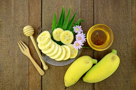 Thai beauty and anti-aging dessert recipe. Cultivated Banana (Musa sapientum Linn.) with honey on Natural Wood Background.の写真素材