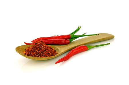 Red hot pepper chilli (Capsicum frutescens L.) with a spoon of cayenne pepper on white background.の写真素材