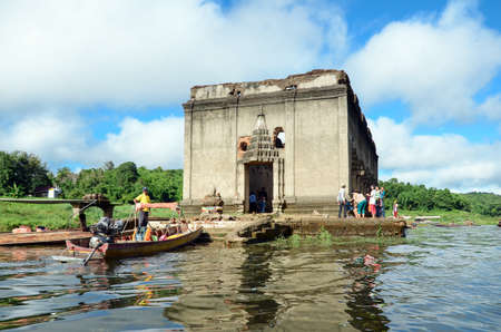 OLD WAT WANG WIWEKARAM SAGKLABURI 12 OCT 2014:Tourists in a long tail boat at the entrance of The Sunken Temple, Wat Wang Wiwekaram, Kanchanaburi, Thailand.のeditorial素材