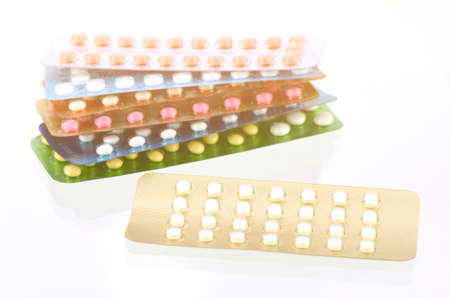 Mini-pills with oral contraceptive pills background in warm light tone.の写真素材