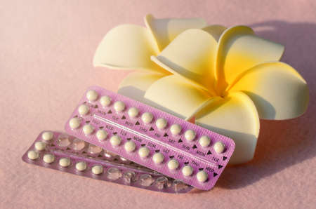 Oral contraceptive with frangipani flowers on pink frieze cloth background.の写真素材