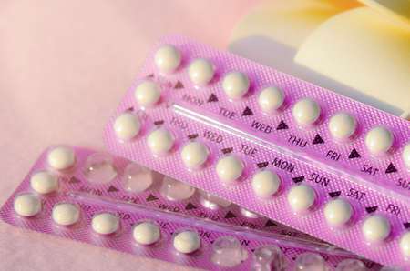 Oral contraceptive with frangipani flowers on pink frieze cloth background with warm light tone.の写真素材