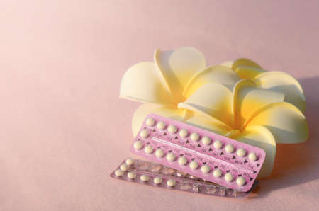 Oral contraceptive with frangipani flowers on pink frieze cloth background with warm light tone.の写真素材