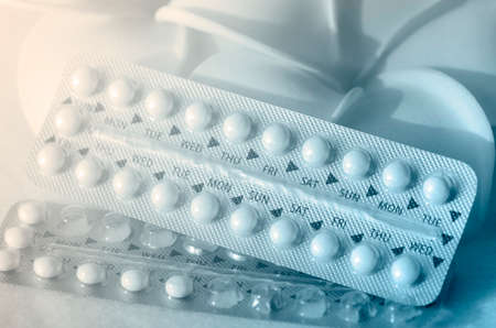 Oral contraceptive with frangipani flowers on pink frieze cloth background with warm light tone.の写真素材