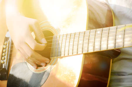 Close-up of hand playing guitar in warm light tone.の写真素材