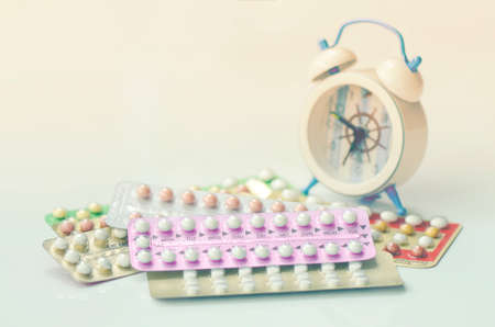 Oral contraceptive pills with alarm clock background in time reminder for taking pills.の写真素材