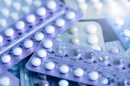 Oral contraceptive pill on pharmacy counter with colorful pills strips background.の写真素材