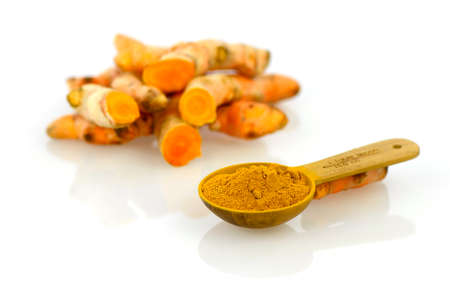 Turmeric roots on white background with teaspoonful of Turmeric roots  powder.の写真素材