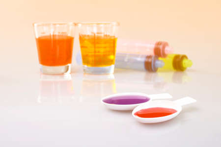Medicinal cup, oral syringe and teaspoon filled with oral syrup medicine.の写真素材