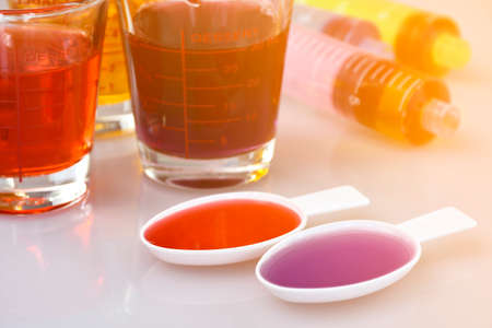 Medicinal cup, oral syringe and teaspoon filled with oral syrup medicine.の写真素材