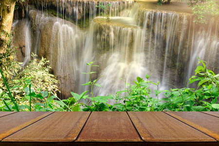 Empty wood table with beautiful scenic of the waterfall and green leaves for refreshing and relaxing background.の写真素材
