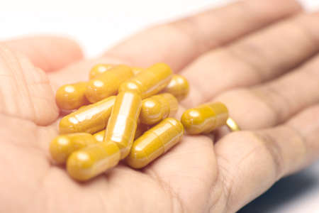Cumin powder in transparent hard gelatin capsule. Herbal medicine capsules on hand with white background.の写真素材
