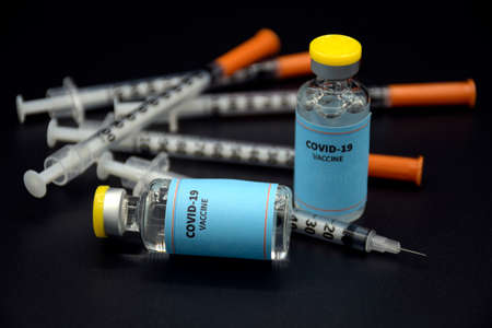 Sample of COVID-19 vaccine and syringe on black background. COVID-19 Vaccine or SARS-CoV-2 Vaccine...