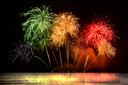 Colorful fireworks celebration from the sea with the midnight sky background.