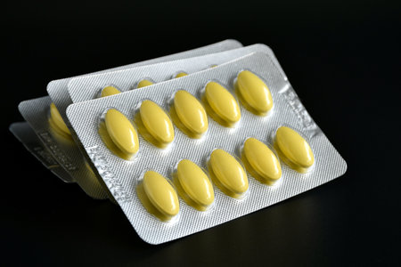 Yellow coated compress tablet in blister pack isolated on black background.の写真素材