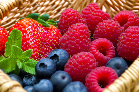 Fresh and organic strawberry, blueberry, raspberry and mint leaves in rattan basket. Generative AI illustration.の素材