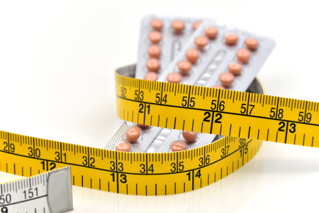 Contraceptive pill strips and yellow tape measurement on white background in weight control concept.の写真素材