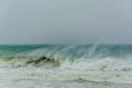 angry turquoise green color massive rip curl of a waves as it barrel rolls along the ocean. wild waves pound the coastline of chabahar in stormy day with cloudy sky close to coastline ,oman seaの写真素材